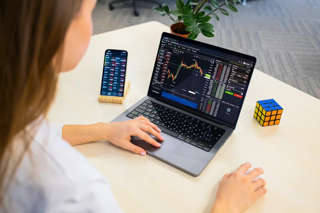 Seorang wanita muda sedang menganalisis grafik saham di laptopnya, menunjukkan proses belajar investasi.